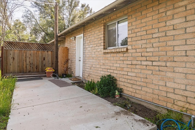 property entrance featuring a patio, fence, and brick siding