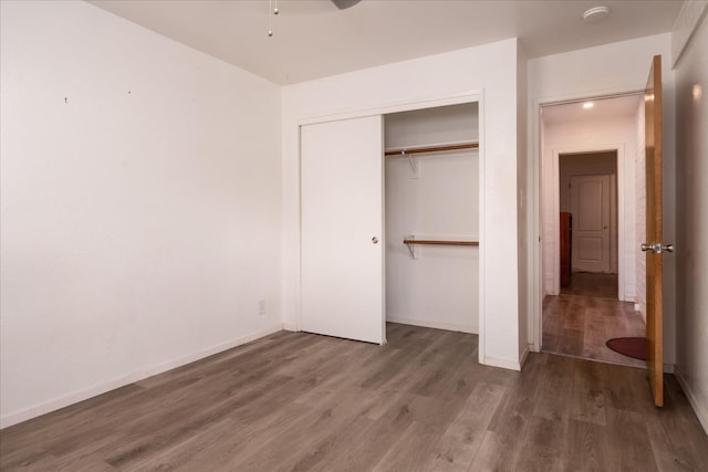 unfurnished bedroom featuring a closet, baseboards, and wood finished floors