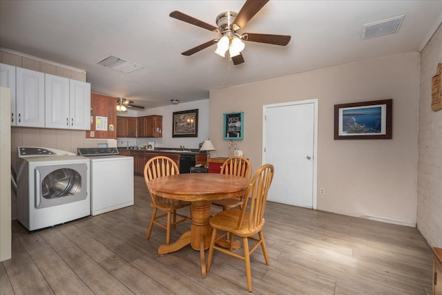 dining area featuring visible vents, washing machine and clothes dryer, light wood-style flooring, and ceiling fan