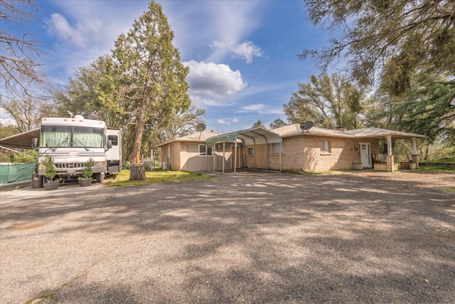 exterior space featuring brick siding, driveway, and a detached carport
