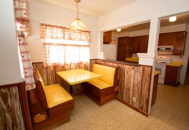 dining room featuring breakfast area, light floors, and a wainscoted wall