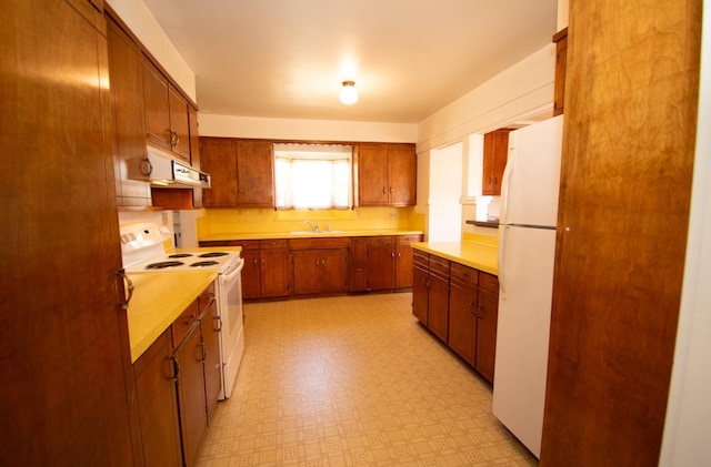 kitchen with under cabinet range hood, white appliances, light countertops, and light floors