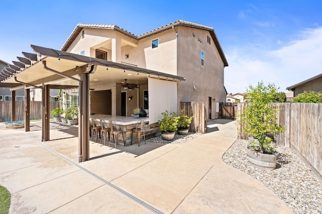 1905 E Via Fiore Ave, Fresno, CA 93730 - back of property featuring a patio, a fenced backyard, outdoor dry bar, and stucco siding