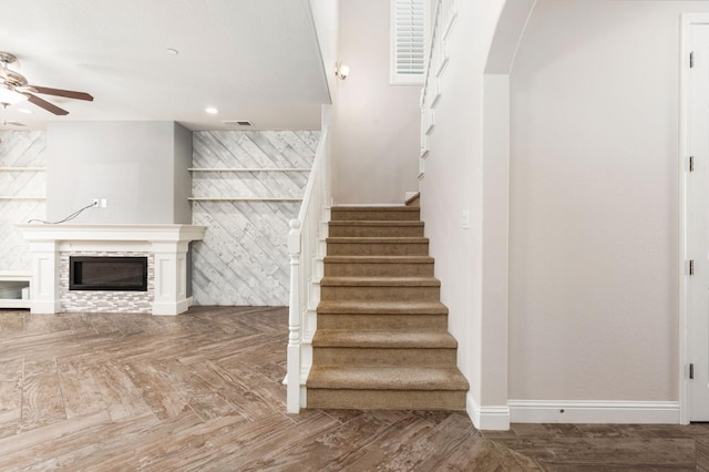 1905 E Via Fiore Ave, Fresno, CA 93730 - stairway featuring visible vents, baseboards, arched walkways, a ceiling fan, and a glass covered fireplace