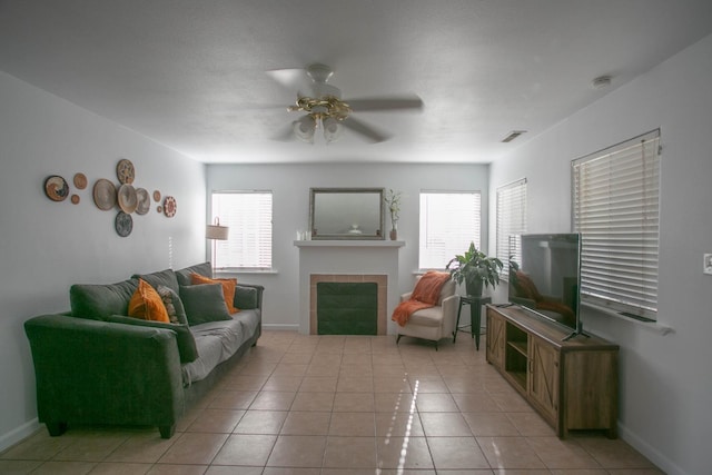 living room featuring visible vents, a ceiling fan, light tile patterned floors, and a tiled fireplace