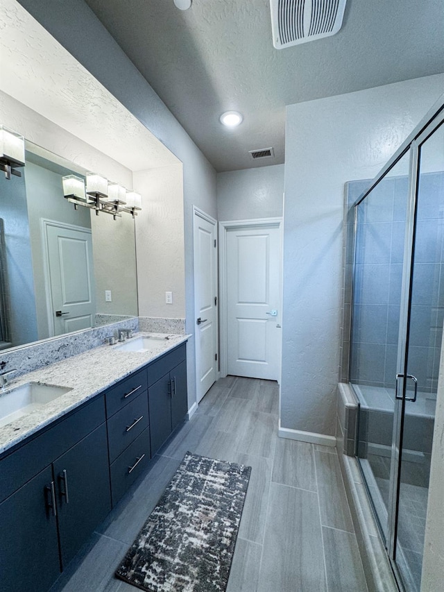3395 Las Rosas Ave, Clovis, CA 93619 - full bath featuring double vanity, a chandelier, a shower stall, a textured ceiling, and wood finished floors