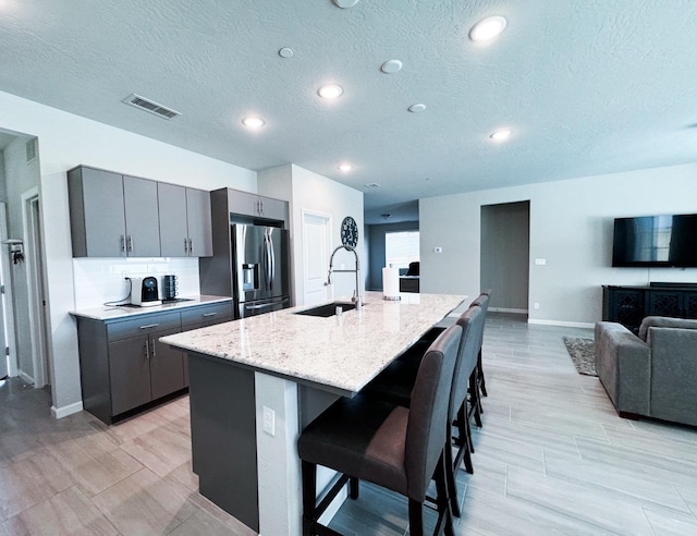 3395 Las Rosas Ave, Clovis, CA 93619 - kitchen with stainless steel fridge, a breakfast bar, gray cabinetry, a textured ceiling, and recessed lighting