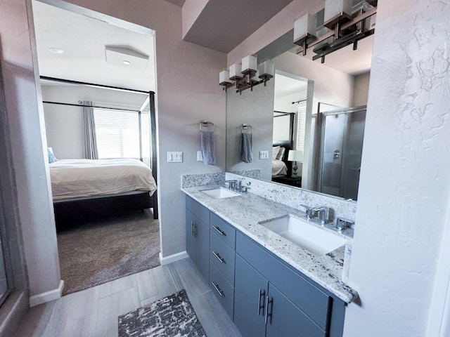 3395 Las Rosas Ave, Clovis, CA 93619 - ensuite bathroom featuring double vanity, a shower stall, a textured wall, and wood finished floors