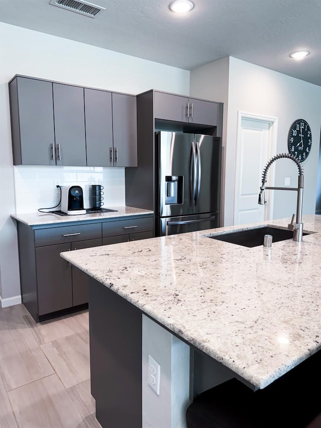 3395 Las Rosas Ave, Clovis, CA 93619 - kitchen with stainless steel fridge with ice dispenser, gray cabinetry, light stone countertops, backsplash, and recessed lighting