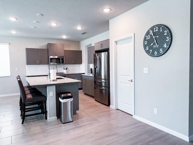 3395 Las Rosas Ave, Clovis, CA 93619 - kitchen featuring appliances with stainless steel finishes, a center island with sink, a kitchen breakfast bar, recessed lighting, and backsplash