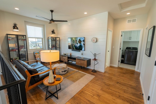 living room with washer / clothes dryer, attic access, a ceiling fan, visible vents, and wood finished floors
