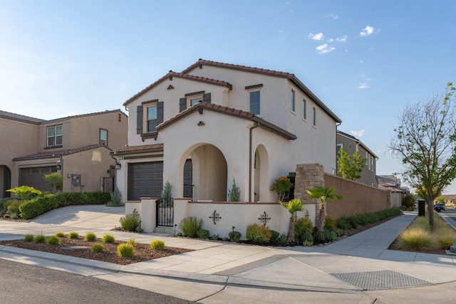 mediterranean / spanish-style house with stucco siding, driveway, a fenced front yard, a garage, and a tiled roof