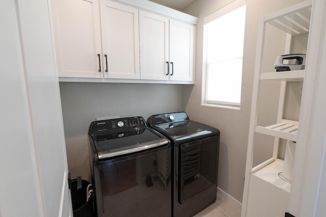 washroom with cabinet space, baseboards, separate washer and dryer, and light tile patterned flooring