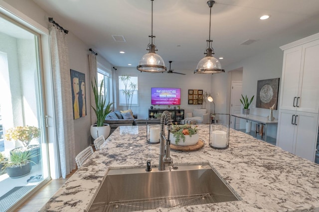 kitchen featuring white cabinets, light stone countertops, and open floor plan