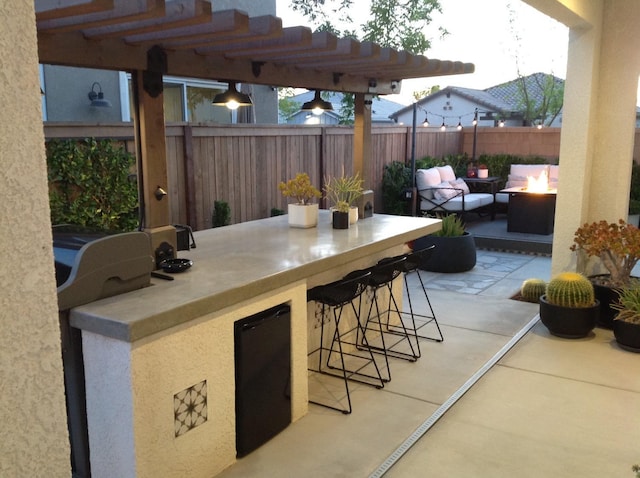 view of patio / terrace with a fire pit, outdoor dry bar, and fence