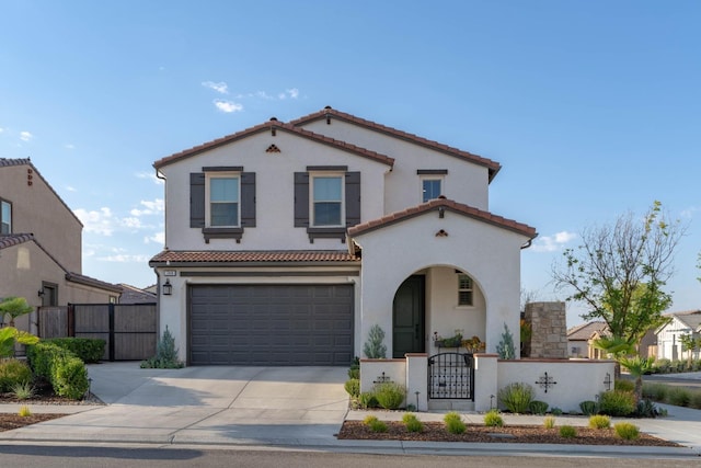 mediterranean / spanish-style home featuring driveway, a fenced front yard, a garage, a tiled roof, and a gate