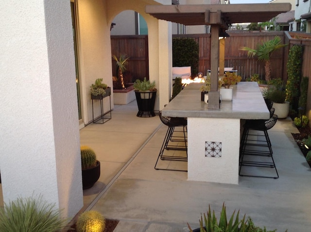 view of patio with a pergola, outdoor dry bar, and fence