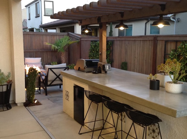 view of patio with a pergola, exterior kitchen, outdoor wet bar, a fenced backyard, and grilling area