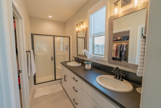 full bath featuring tile patterned floors, a sink, a spacious closet, and a stall shower