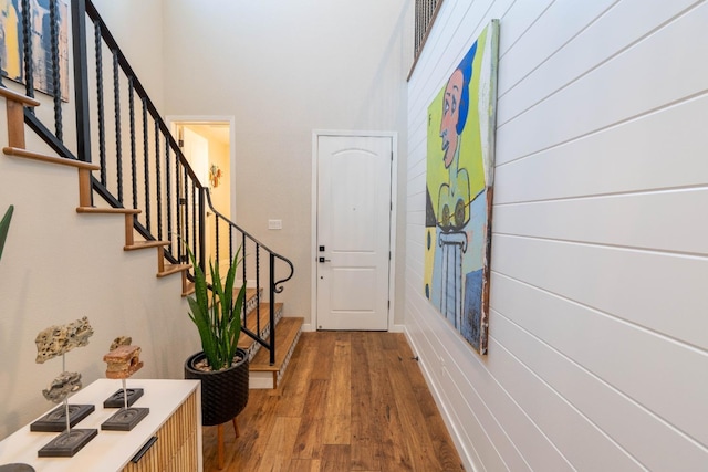 foyer entrance featuring wood finished floors, a towering ceiling, baseboards, and stairway