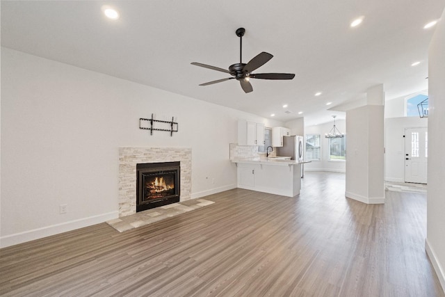 1125 N Purdue Ave, Clovis, CA 93611 - unfurnished living room featuring lofted ceiling, a sink, a stone fireplace, a ceiling fan, and light wood finished floors
