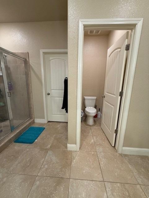 bathroom featuring visible vents, toilet, a stall shower, baseboards, and tile patterned floors