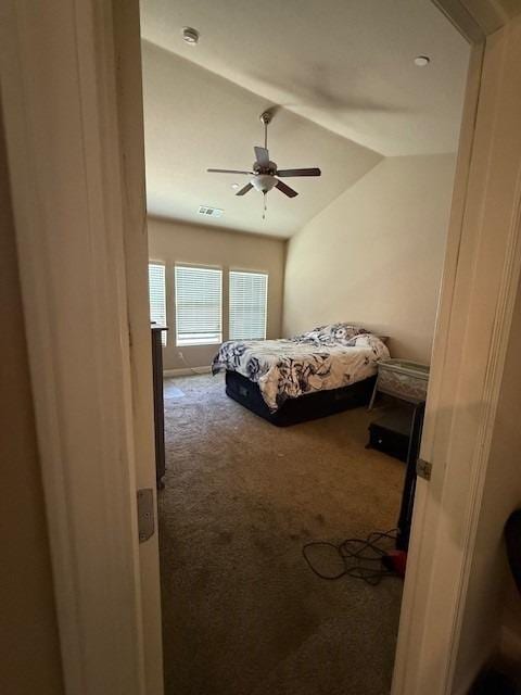 carpeted bedroom featuring a ceiling fan, vaulted ceiling, and visible vents