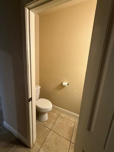 bathroom featuring toilet, tile patterned floors, and baseboards