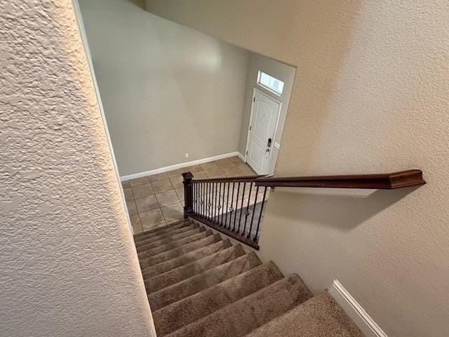 stairway with tile patterned floors and baseboards