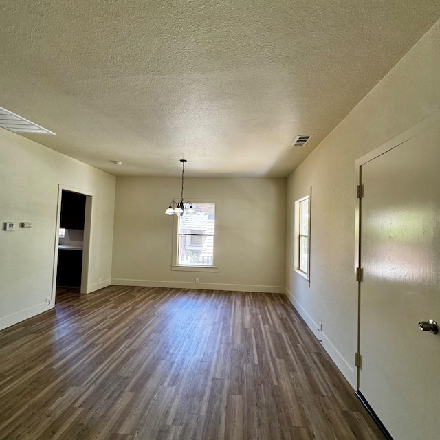 unfurnished dining area featuring a wealth of natural light, dark wood-style flooring, and a chandelier
