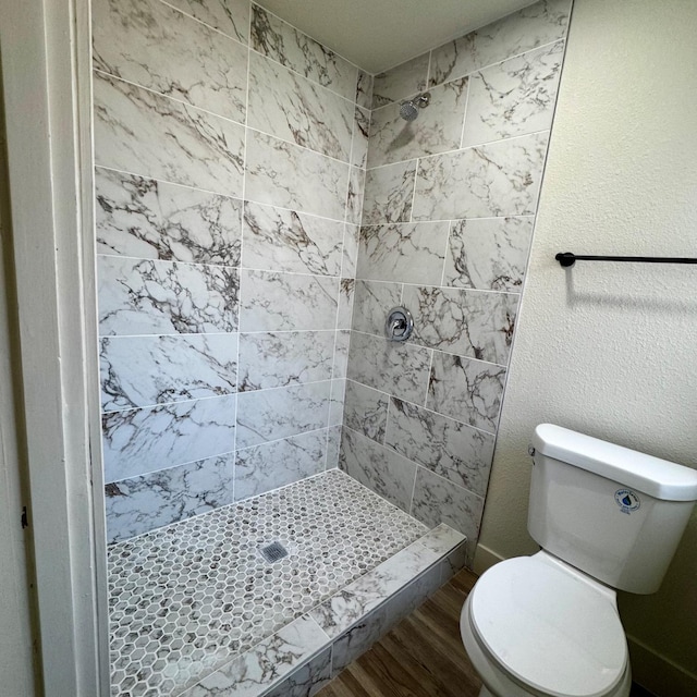 bathroom featuring toilet, wood finished floors, and a shower stall