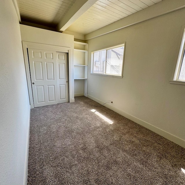 unfurnished bedroom featuring wood ceiling, beamed ceiling, multiple windows, and carpet