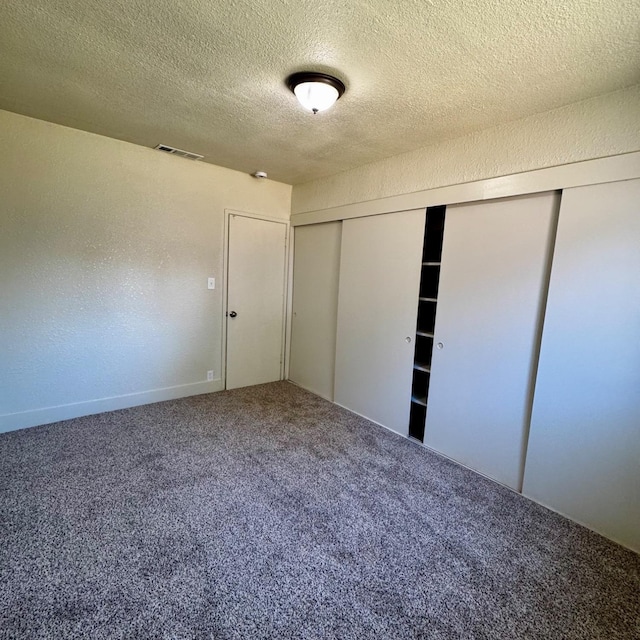 unfurnished bedroom with carpet flooring, visible vents, a closet, and a textured ceiling