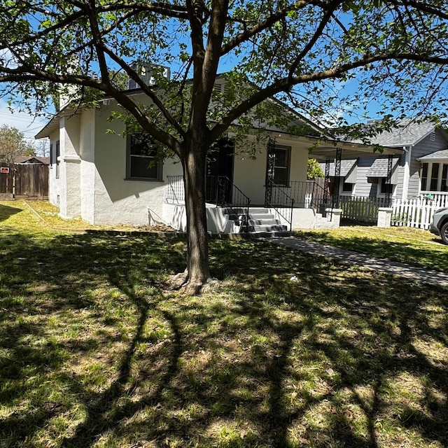exterior space with stucco siding, fence, and a lawn