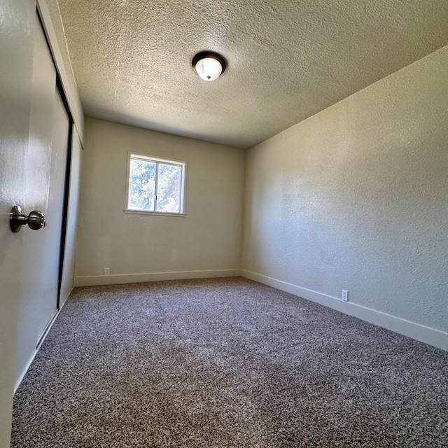 carpeted empty room featuring baseboards, a textured wall, and a textured ceiling