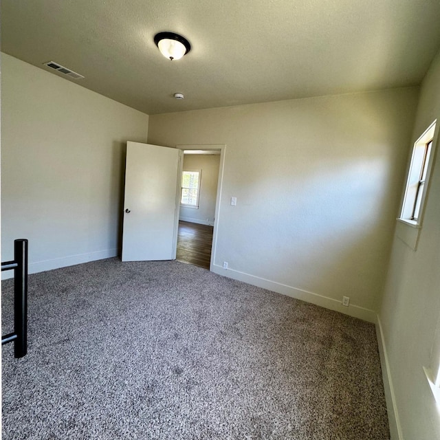 unfurnished room featuring carpet, visible vents, and baseboards