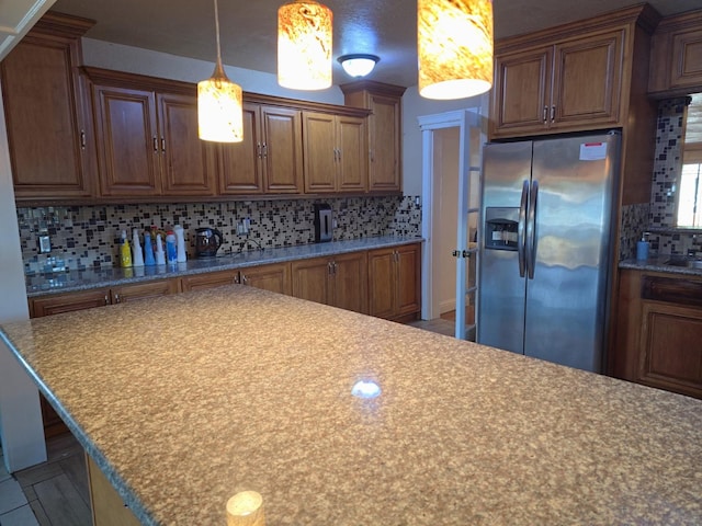 3525 Mayfair Dr N, Fresno, CA 93703 - kitchen with stainless steel fridge, decorative backsplash, brown cabinetry, and hanging light fixtures