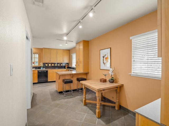 6043 N Forkner Ave, Fresno, CA 93711 - kitchen with dishwasher, light brown cabinetry, backsplash, a kitchen bar, and track lighting