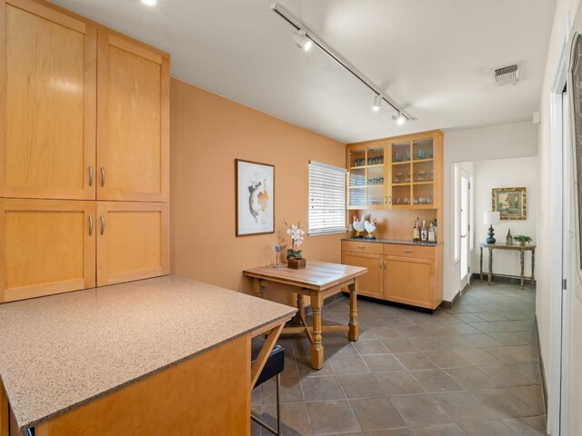 6043 N Forkner Ave, Fresno, CA 93711 - kitchen with glass insert cabinets, track lighting, dark tile patterned flooring, light stone countertops, and a kitchen breakfast bar