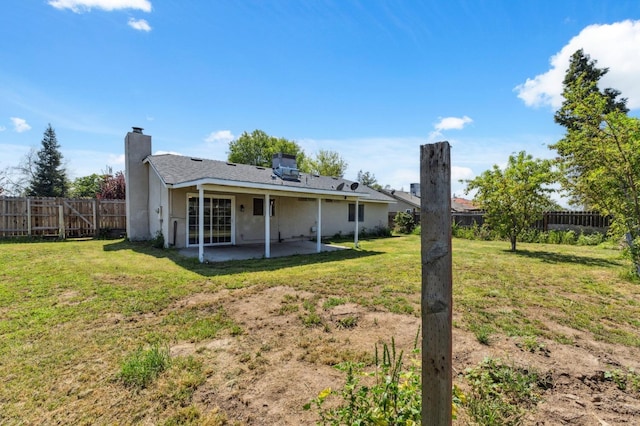 704 Rosehill Dr, Chowchilla, CA 93610 - rear view of house featuring stucco siding, a chimney, a patio area, a fenced backyard, and a lawn