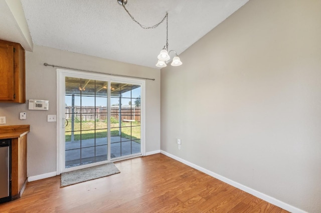 704 Rosehill Dr, Chowchilla, CA 93610 - unfurnished dining area with a chandelier, light wood-type flooring, and baseboards