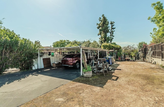 exterior space featuring a detached carport, fence, and driveway