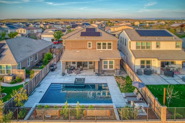 back of property with solar panels, a residential view, outdoor lounge area, and a fenced backyard