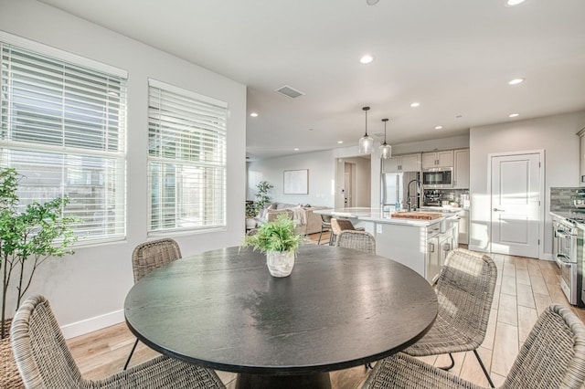dining room featuring light wood-type flooring, baseboards, visible vents, and recessed lighting