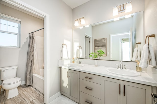 bathroom featuring double vanity, toilet, baseboards, and a sink