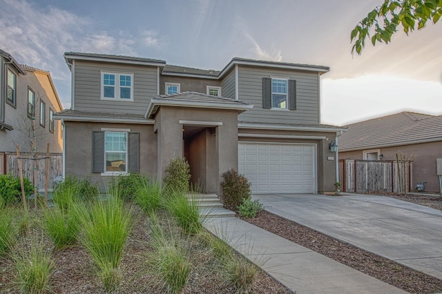 traditional-style home featuring concrete driveway, an attached garage, stucco siding, and fence