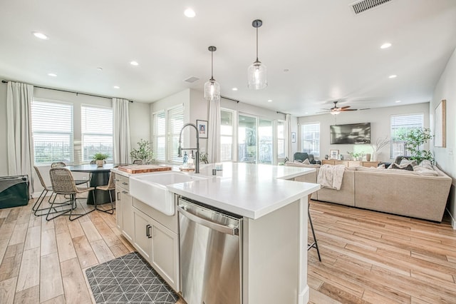 kitchen with a sink, a healthy amount of sunlight, recessed lighting, light wood finished floors, and stainless steel dishwasher