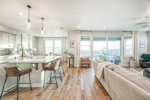 kitchen featuring light wood-style flooring, a breakfast bar, open floor plan, visible vents, and light countertops