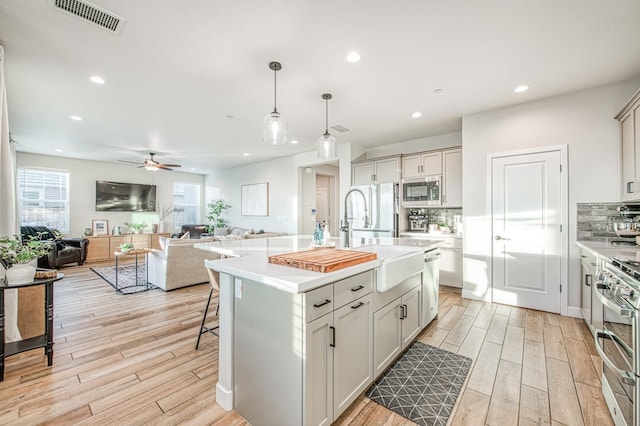 kitchen featuring light wood-type flooring, stainless steel appliances, visible vents, and a sink