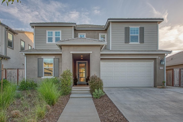 traditional-style home with fence, a garage, stucco siding, and concrete driveway